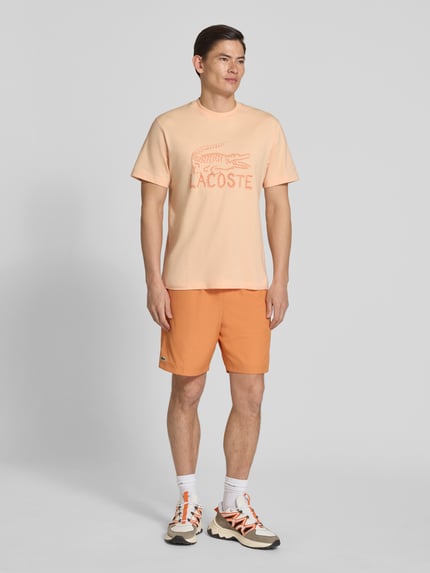 Männermodel trägt Regular Fit T-Shirt aus reiner Baumwolle von Lacoste, Optik: unifarben, Logo-Print, Rundhals, Kurzarm, Ganzkörperansicht von vorne.