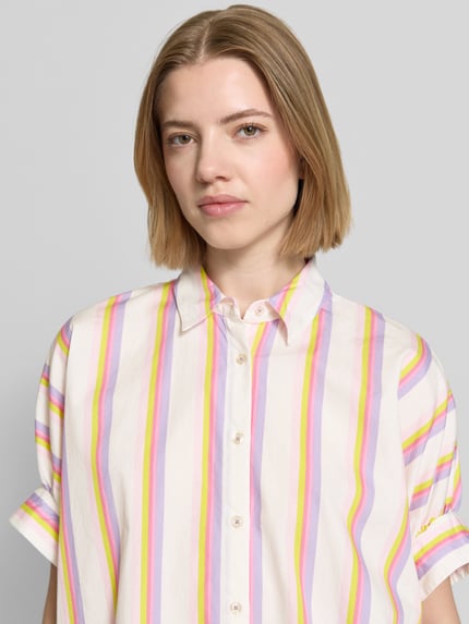 Frauenmodel trägt Relaxed Fit Bluse im Allover-Look von Emily Van den Bergh aus reiner Baumwolle mit Hemdblusenkragen und Knopfleiste, Nahaufnahme Oberkörper.