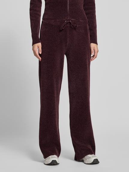 Frauenmodel trägt Sweathose mit Tunnelzug von Juicy Couture in Unifarbe, elastischer Bund mit Kordeln, samtige Textur, Nahaufnahme Oberkörper