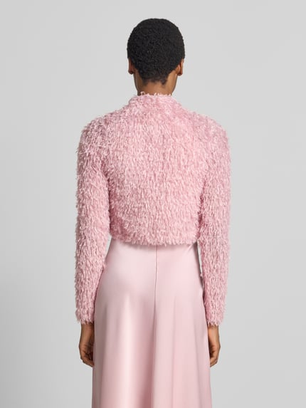 Frauenmodel trägt Cropped Jacke aus Effektgarn mit V-Ausschnitt von SWING in Rosa, Slim Fit, strukturierte Oberfläche, Ganzkörperansicht Rückansicht.