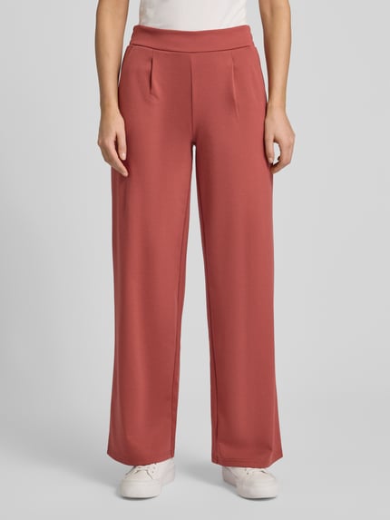 Frauenmodel trägt Wide Fit Stoffhose mit Viskose-Anteil Modell 'Kate' von ICHI in Rot, Bundfalten, Elastischer-Material-Mix, Ganzkörperansicht von vorne.