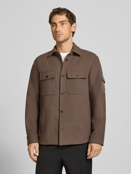 Męski model nosi Regular Fit Hemdjacke mit Kentkragen und Brusttaschen von Armani Exchange, brąz, krój regular fit, Kołnierzyk typu kent, kieszenie na piersi, listwa guzikowa, długość tyłu w rozmiarze M: 75 cm, Ganzkörperansicht von vorne.