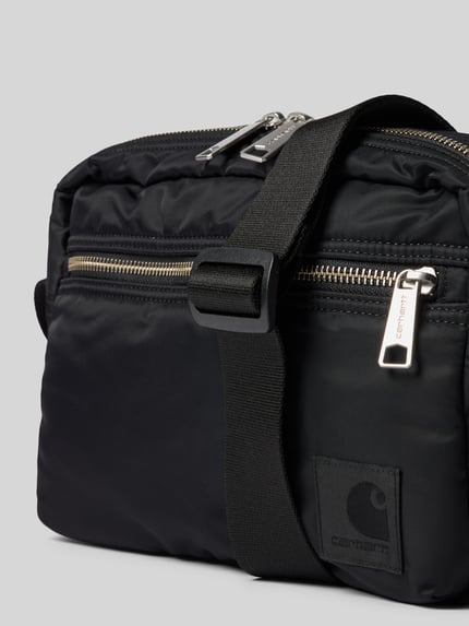 Produktfoto, Tasche mit Logo-Print von Carhartt Work In Progress in Schwarz, glatte Textur, silberne Reißverschlüsse, wasserabweisend, Nahaufnahme