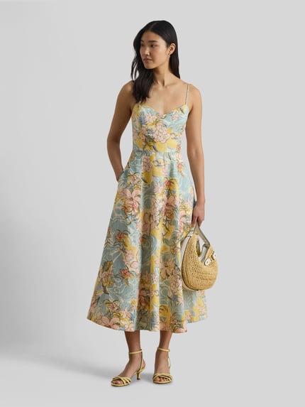Vrouwenmodel draagt 'Körpernahes Midikleid aus reinem Leinen' van Lauren Ralph Lauren in all-over bloemenmotief, a-lijn fit, midilengte, hartvormige hals, spaghettibandjes, zij-steekzakken, sluiting met verborgen ritssluiting, haak en oog, gemaakt van puur linnen, pastelkleuren, gladde textuur. Ganzkörperansicht van voren.