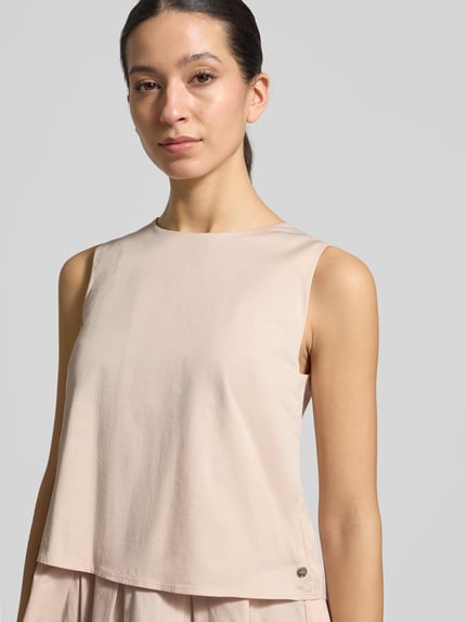 Frauenmodel trägt Blusenshirt mit Volantsaum und Rundhalsausschnitt von Marc Cain, Baumwoll-Viskose-Mix, Gerader-Schnitt, Nahaufnahme Oberkörper. Rückenreißverschluss, Rückenlänge 59 cm bei Größe 36.