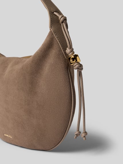 Produktfoto, Schultertasche in Braun mit goldfarbenem Logo-Detail, samtiger Wildleder-Look, Modell 'Thess' von Coccinelle, Reißverschluss-Hauptfach, Tunnelzug-Schulterriemen, Maße 34x26x4 cm, Riemenlänge 44 cm