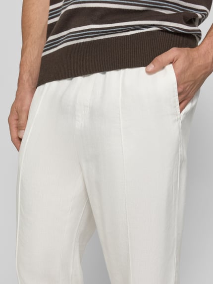 Męski model nosi Straight Fit Schmale Hose aus Leinen-Lyocell-Mix Modell 'CINO' od HUGO, gładka faktura, jasna biel, flammgarn, kieszenie boczne, zbliżenie na górną część ciała, widok z przodu.