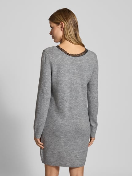 Frauenmodel trägt tailliertes Strickkleid mit V-Ausschnitt Modell 'TAMMY' von Only, graues Melange, Spitzenbesatz, knielang, Rückansicht.