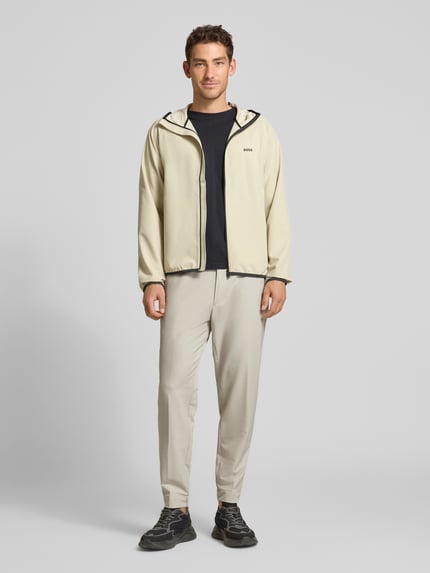 Männermodel trägt Tapered Fit Stoffhose mit Tunnelzug Modell 'T_FLEX' von BOSS Green in Unifarbe mit mittelhohem, elastischem Bund, Ganzkörperansicht von vorne.