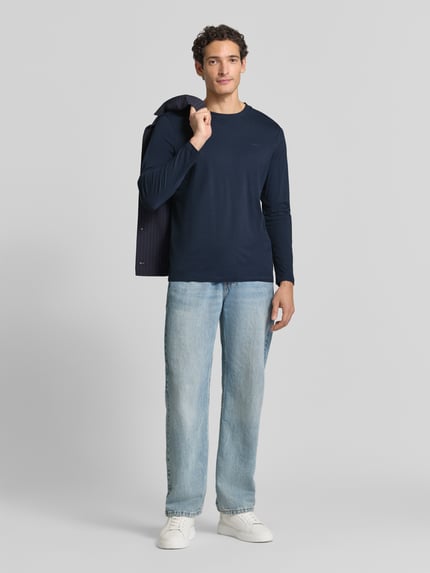 Männermodel trägt Langarmshirt mit Rundhalsausschnitt von S.OLIVER CASUAL, unifarben, dunkelblau, kombiniert mit Jeans und Sneakers, Ganzkörperansicht von vorne.