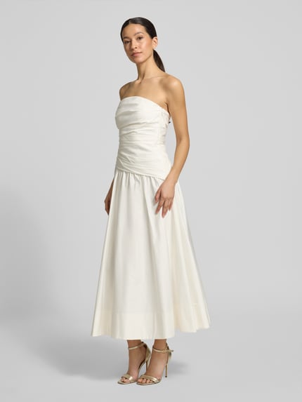 Frauenmodel trägt Cocktailkleid im Off-Shoulder-Look Modell 'Ashton' von Forever New aus Baumwoll-Elasthan-Mix, A-Linie, Midikleid, Ganzkörperansicht von vorne.