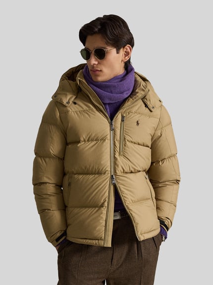 Männermodel trägt hellbraune Regular Fit Daunenjacke mit Logo-Stitching von Polo Ralph Lauren, Herren Daunenjacke, Ganzkörperansicht von vorne.