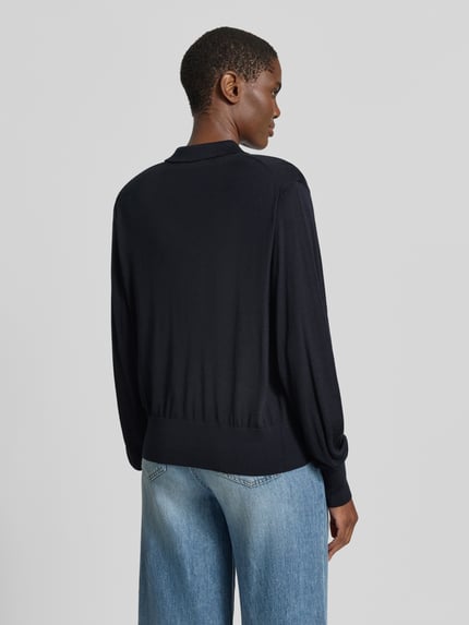 Frauenmodel trägt Regular Fit Cardigan aus reiner Wolle Modell 'BOSTON' von ba&sh in Schwarz, Umlegekragen, elastische Abschlüsse, Rückenlänge 57 cm, Ärmellänge 66 cm, Ganzkörperansicht Rückansicht.