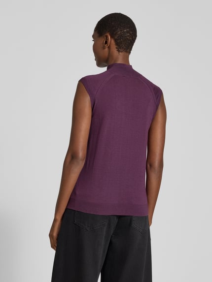 Frauenmodel trägt Pullunder aus Wolle mit Mock Neck von BOSS in unifarbener, matter Strickoptik, Strukturmuster, Ganzkörperansicht Rückansicht.