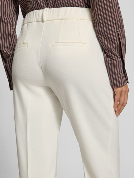 Frauenmodel trägt Regular Fit Hose mit Bügelfalte von Stehmann in Creme, strukturierte Webware, Bundfalte, Eingrifftaschen, Ganzkörperansicht Rückansicht.