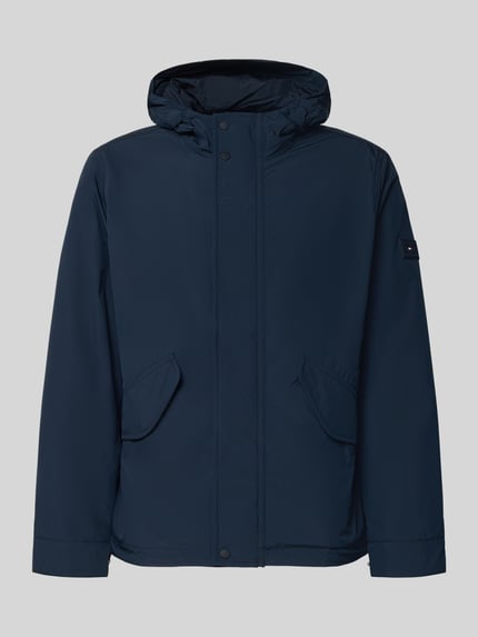 Produktfoto, Regular Fit Funktionsjacke mit Kapuze von Tommy Hilfiger in Dunkelblau, unifarben, wasserabweisend, Zweiwege-Reißverschluss, Kapuze, Label-Applikation, Logo-Patch, lange Ärmel mit Druckknöpfen, Tunnelzug am Saum, seitliche Eingrifftaschen und Napoleontasche, glatte Textur
