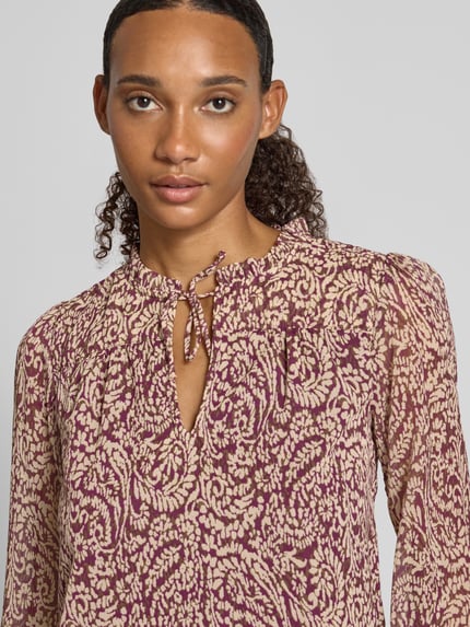 Frauenmodel trägt Regular Fit Langarmbluse mit Bindeverschluss Modell 'DITSY' von ONLY, florales Muster in Beige und Lila, Nahaufnahme Oberkörper, Damen Langarmbluse von ONLY.