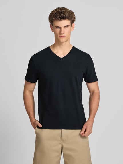 Männermodel trägt T-Shirt aus Baumwoll-Leinen-Mix mit V-Ausschnitt von Superdry, Regular-Fit, Stitching, Rückenlänge 68 cm, schwarze Farbe, glatte Struktur, Ganzkörperansicht von vorne.