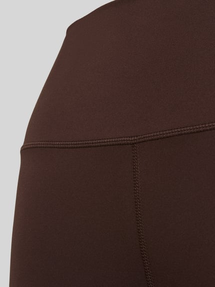 Frauenmodel trägt Slim Fit Leggins mit Logo-Print Modell 'Freesoft' von VARLEY, elastischer Material-Mix, Detailaufnahme.