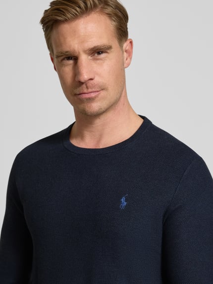 Männermodel trägt dunkelblauen Strickpullover mit Label-Stitching von Polo Ralph Lauren, reine Baumwolle, Nahaufnahme Oberkörper.