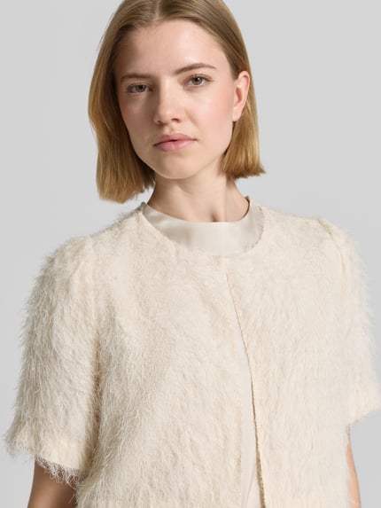 Frauenmodel trägt Regular Fit Bolero mit feinen Fransen von s.Oliver BLACK LABEL, Optik: Unifarben, Rundhals, Haken-Öse, Kurzarm, Nahaufnahme Oberkörper.