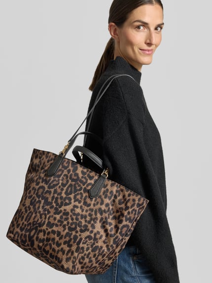 Vrouwenmodel draagt Shopper met afneembare schouderriem van BORBONESE met luipaardprint, zwarte hengsels, grote tas, detailopname schouderriem.