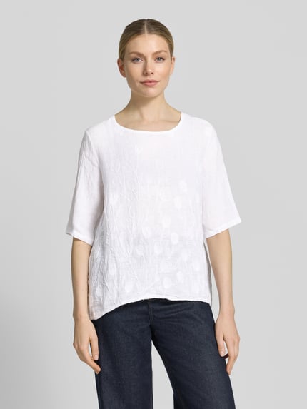 Frauenmodel trägt Blusenshirt mit Stitchings Modell 'No44raa' von ZABAIONE, Relaxed-Fit, weiß, Rundhalsausschnitt, 1/2-Arm, Ganzkörperansicht von vorne.