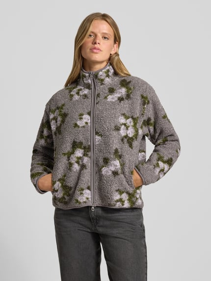 Frauenmodel trägt Regular Fit Teddyjacke mit Allover-Muster Modell 'AUTUMN' von PIECES in Grau mit weißen und grünen Blumen, Damen Fleecejacke, Ganzkörperansicht von vorne.