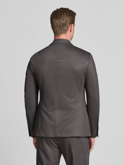 Männermodel trägt Regular Fit Sakko mit Viskose-Anteil Modell 'Data' von CINQUE in Grau, glatte Textur, Ganzkörperansicht Rückansicht. Das Sakko zeigt einen klassischen Reverskragen, Pattentaschen und eine 2-Knopfleiste, gefertigt aus elastischem Material-Mix.