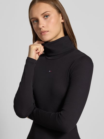 Frauenmodel trägt Eng anliegendes Freizeitkleid aus Baumwoll-Mix von Tommy Jeans in Schwarz, strukturierte Oberfläche, Nahaufnahme Oberkörper. Damen Freizeitkleid von Tommy Jeans