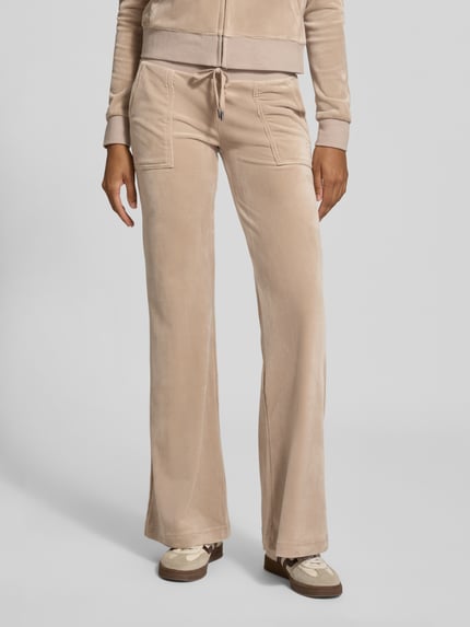 Vrouwenmodel draagt Joggingbroek met trekkoord model 'LAYLA' van Juicy Couture, effen beige, katoenmix met steekzakken, detailopname voorkant.