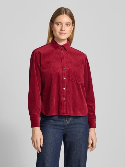 Vrouwenmodel draagt Regular Fit Hemdbluse aus Cord van Christian Berg Woman in rood, met overhemdkraag, borstzak, knoopsluiting, corduroy structuur, ruglengte bij maat 36: 59 cm, mouwlengte bij maat 36: 58 cm, voorkant bovenlichaam close-up.