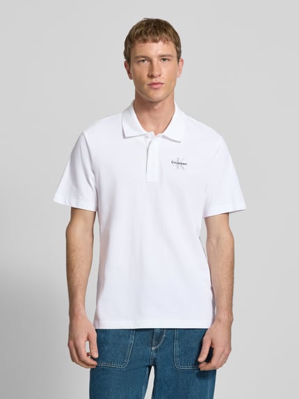 Männermodel trägt Easy Fit Poloshirt mit Polokragen von Calvin Klein Jeans aus reiner Baumwolle, mit Label-Stitching, Ganzkörperansicht von vorne.