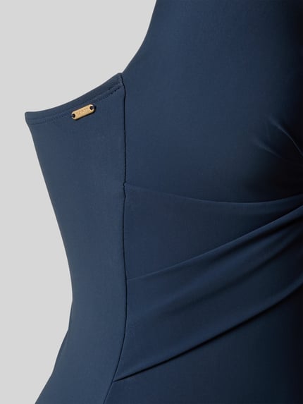 Frauenmodel trägt Badeanzug mit tiefem V-Ausschnitt Modell 'SOLID' von Barts aus marineblauem Material-Mix mit Stretch-Anteil, Detailaufnahme.