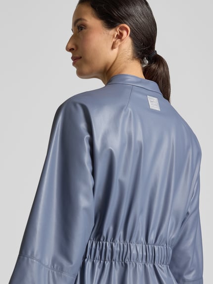 Frauenmodel trägt Blazer in Leder-Optik mit Stehkragen von Marc Cain in Blau, tailliert, glatte Oberfläche, Rückansicht, Nahaufnahme Oberkörper. Rückenlänge 54 cm, Brustweite 48 cm, Ärmellänge 49 cm, 3/4-Arm, Reißverschluss.