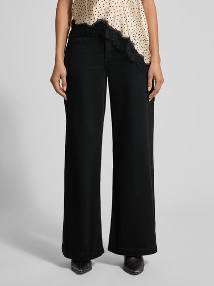 Frauenmodel trägt Wide Leg Jeans mit Eingrifftaschen Modell 'LIA' von Mango, schwarze Baumwolle, Nahaufnahme Oberkörper bis Füße.