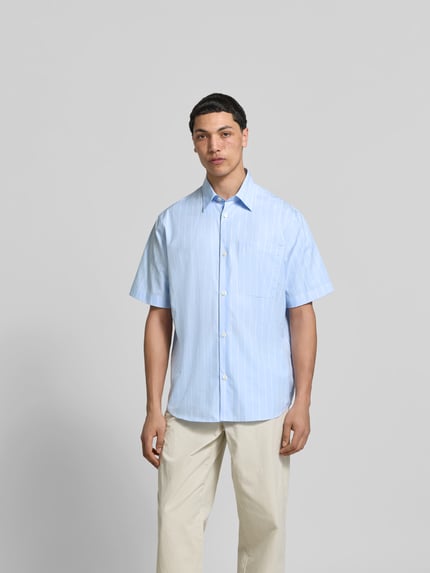 Męski model nosi Classic Fit Freizeithemd aus Baumwolle von ANNARR, jasnoniebieski z białymi paskami, brustasza, z krótkim rękawem, długość tyłu w rozmiarze M: 81 cm, szerokość ramion w rozmiarze M: 48 cm, długość rękawów w rozmiarze M: 28 cm, krój klasyka, na całej długości listwa guzikowa, koszula casualowa, bawełna, Ganzkörperansicht von vorne