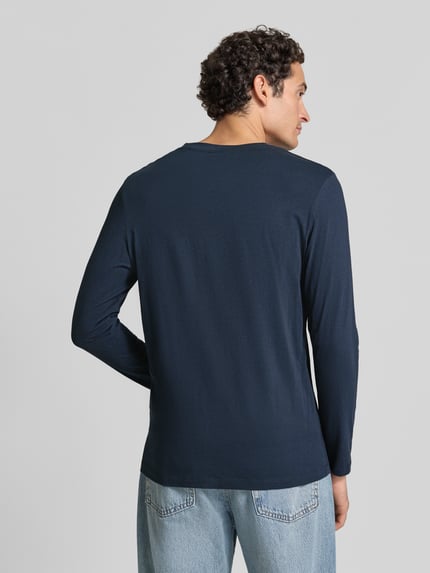 Männermodel trägt dunkelblaues, unifarbenes Langarmshirt mit Rundhalsausschnitt von S.OLIVER CASUAL, glatte Textur, Ganzkörperansicht Rückansicht.