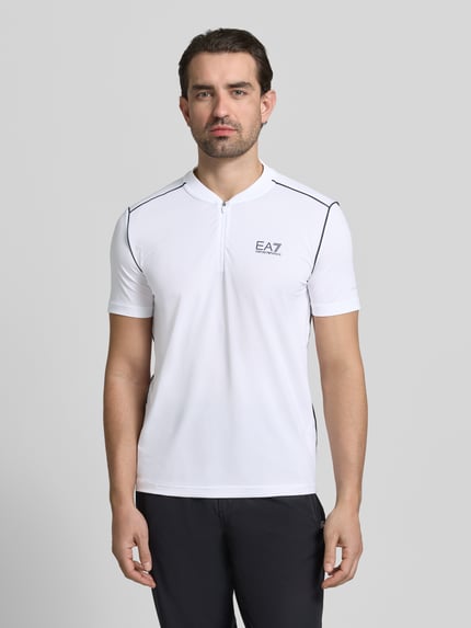 Männermodel trägt Regular Fit T-Shirt mit Stehkragen von EA7 Emporio Armani in Weiß mit Label-Print, Reißverschluss, Ganzkörperansicht von vorne.