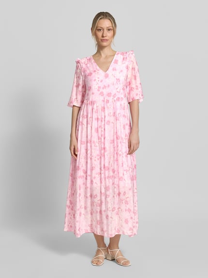 Vrouwenmodel draagt maxi-jurk uit viscosemix met model 'Melie' van mbyM, bloemen all-over print, halflange mouwen, met ruches, getailleerd, roze tinten, gladde stof, lengte over de enkels. Ganzkörperansicht von vorne.