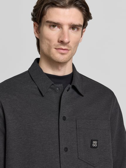 Mannelijk model draagt Oversized Hemdjacke aus Baumwoll-Mix Modell 'ENASO' van HUGO in effen gemêleerde twill, borstzak met label patch, Nahaufnahme bovenlichaam.