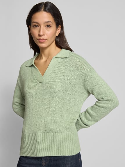 Frauenmodel trägt Strickpullover mit V-Ausschnitt von Fynch-Hatton in Mintgrün, Baumwoll-Mix mit Stretch-Anteil, Resort-Kragen, gerippte Abschlüsse, lockerer Schnitt, Ganzkörperansicht von vorne.