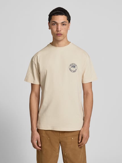Männermodel trägt T-Shirt mit Logo und Rundhalsausschnitt von BLKVIS in Beige, Reine Baumwolle, Regular-Fit, Rückenlänge 70 cm, Ganzkörperansicht von vorne.