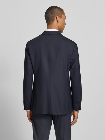 Männermodel trägt dunkelblaues Slim Fit Sakko mit Schurwoll-Anteil, Modell 'Totti' von CINQUE, glatte Textur, Ganzkörperansicht Rückansicht.