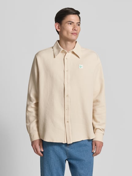 Männermodel trägt Regular Fit Freizeithemd mit Label-Patch von American Vintage, Reine Baumwolle, Kentkragen, Knopfleiste, Ganzkörperansicht von vorne.