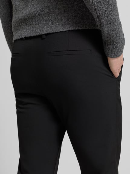 Männermodel trägt Chino mit Eingrifftaschen Modell 'ROBERT' von SELECTED HOMME, Unifarbenes-Design, Material-Mix mit Viskose-Anteil, körpernaher Schnitt, Detailaufnahme Rückansicht.