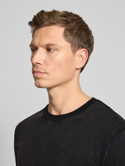 Männermodel trägt T-Shirt mit geripptem Rundhalsausschnitt von Drykorn, reine Baumwolle, Regular Fit, schwarze Farbe, Nahaufnahme Oberkörper.