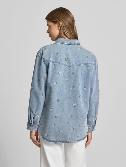 Frauenmodel trägt Relaxed Fit Jeansbluse aus reiner Baumwolle Modell 'VERA' von Only in Denim-Optik mit florale-Stickereien, Rückenpasse, verdeckte Knopfleiste, Hemdblusenkragen, Langarm und Manschette, Rumpfabschluss abgerundet, Material: reine Baumwolle, Ganzkörperansicht Rückansicht.