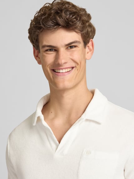 Männermodel trägt Slim Fit Poloshirt aus Frottee von Superdry in Weiß, Reine Baumwolle, Kurzärmelig, Nahaufnahme Oberkörper.