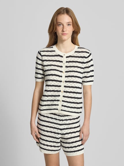 Vrouwenmodel draagt Slim Fit Cardigan in tricotlook van REVIEW, puur katoen, ronde hals, halflange mouwen, knoopsluiting, ruglengte 50 cm, maat S, zwart-witte strepen, zacht textuur, vooraanzicht volledige lichaamsopname.